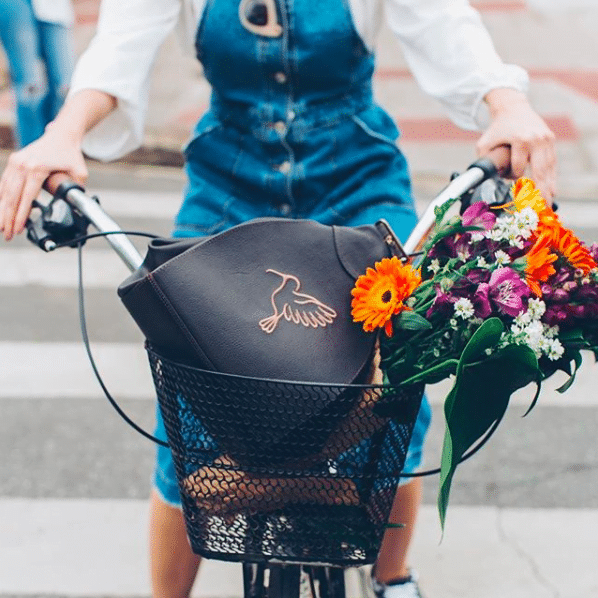 Woman cycling with flowers in basket